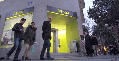 Personas pasando por delante de una oficina de Bankia