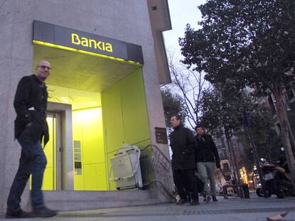 Personas pasando por delante de una oficina de Bankia