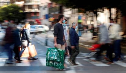 Varias personas cargan con sus bolsas en una calle de Valencia tras realizar sus compras navideñas el pasado mes de diciembre.