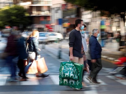 Varias personas cargan con sus bolsas en una calle de Valencia tras realizar sus compras navideñas el pasado mes de diciembre.