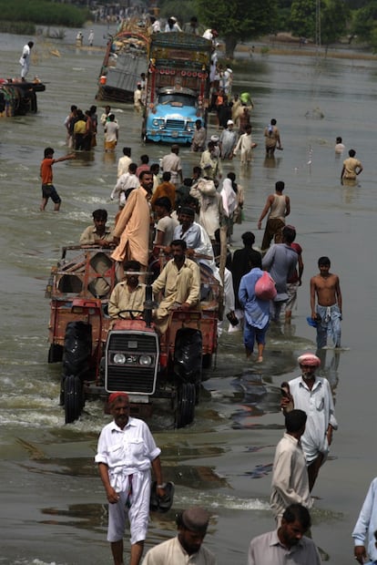 Cientos de personas continúan con su rutina diaria y trasladan sus enseres a pesar de las inundaciones en Pakistán.