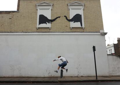 Un patinador salta delante de la fachada en la que Banksy pintó dos elefantes en Fulham (Londres), el 6 de agosto.