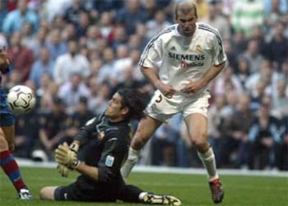 Víctor Valdés despeja el balón desde el suelo ante Zidane.
