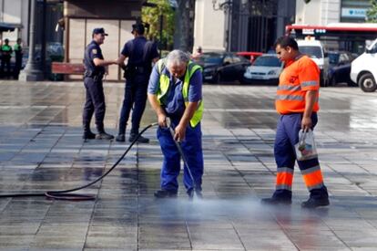Un par de operarios de limpieza limpian el suelo de la plaza del Ayuntamiento de Valencia tras el desalojo esta madrugada.