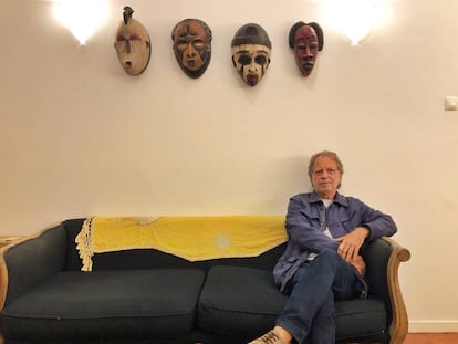 El escritor mozambiqueño Mía Couto posa bajo una colección de máscaras africanas en Maputo.