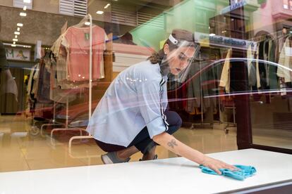 Una joven limpia el escaparate de una tienda de complementos en el centro de Santa Cruz de Tenerife, este martes.