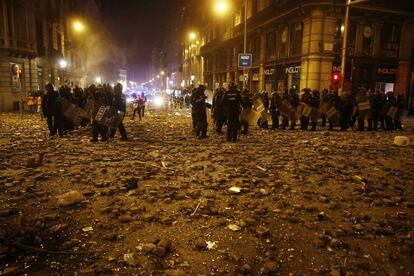 Rubble thrown by protestors surrounds riot police in Barcelona on Friday night.