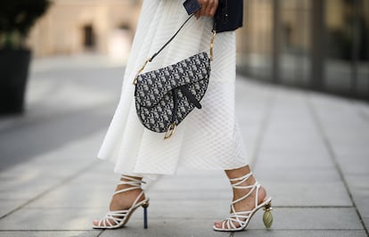 Una mujer pasea por las calles de París con un bolso de Dior.