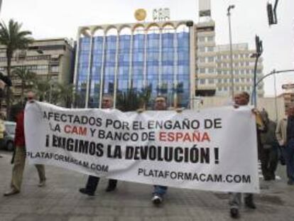 Varios afectados portan una pancarta ante las oficinas de la sede central de la CAM en Alicante. EFE/Archivo