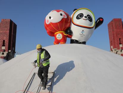 Un operario pinta junto a las mascotas de los Juegos Olímpicos de Invierno Pekín 2022.