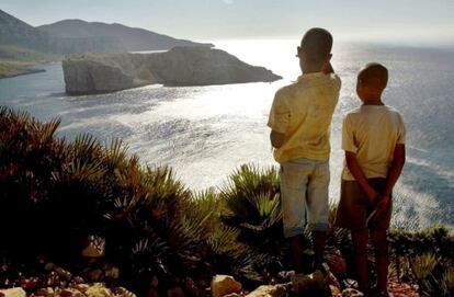 Dos ni&ntilde;os miran hacia el islote de Perejil. 