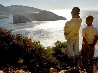 Dos ni&ntilde;os miran hacia el islote de Perejil. 