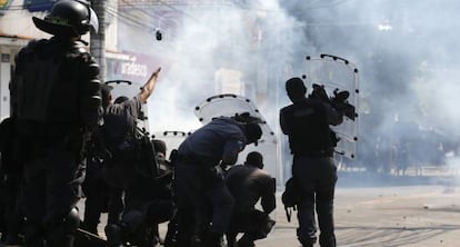 Agentes de polic&iacute;a se protegen y lanzan granadas de gas lacrim&oacute;geno contra los &#039;okupas&#039;.