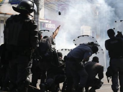 Agentes de polic&iacute;a se protegen y lanzan granadas de gas lacrim&oacute;geno contra los &#039;okupas&#039;.