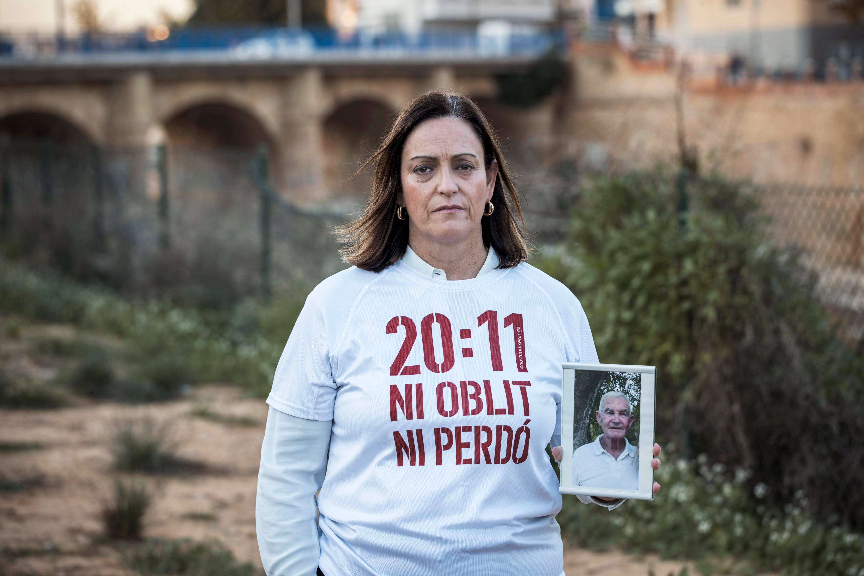 Ana María Gil García posa junto al barranco de Catarroja con una fotografía de su padre, Pedro Gil Ruiz, fallecido a causa de un infarto agudo de miocardio en su domicilio.