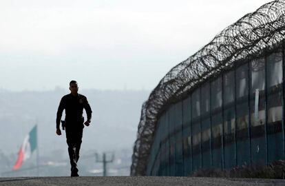 Un agente de la policía de fronteras, junto a la valla en San Diego.
