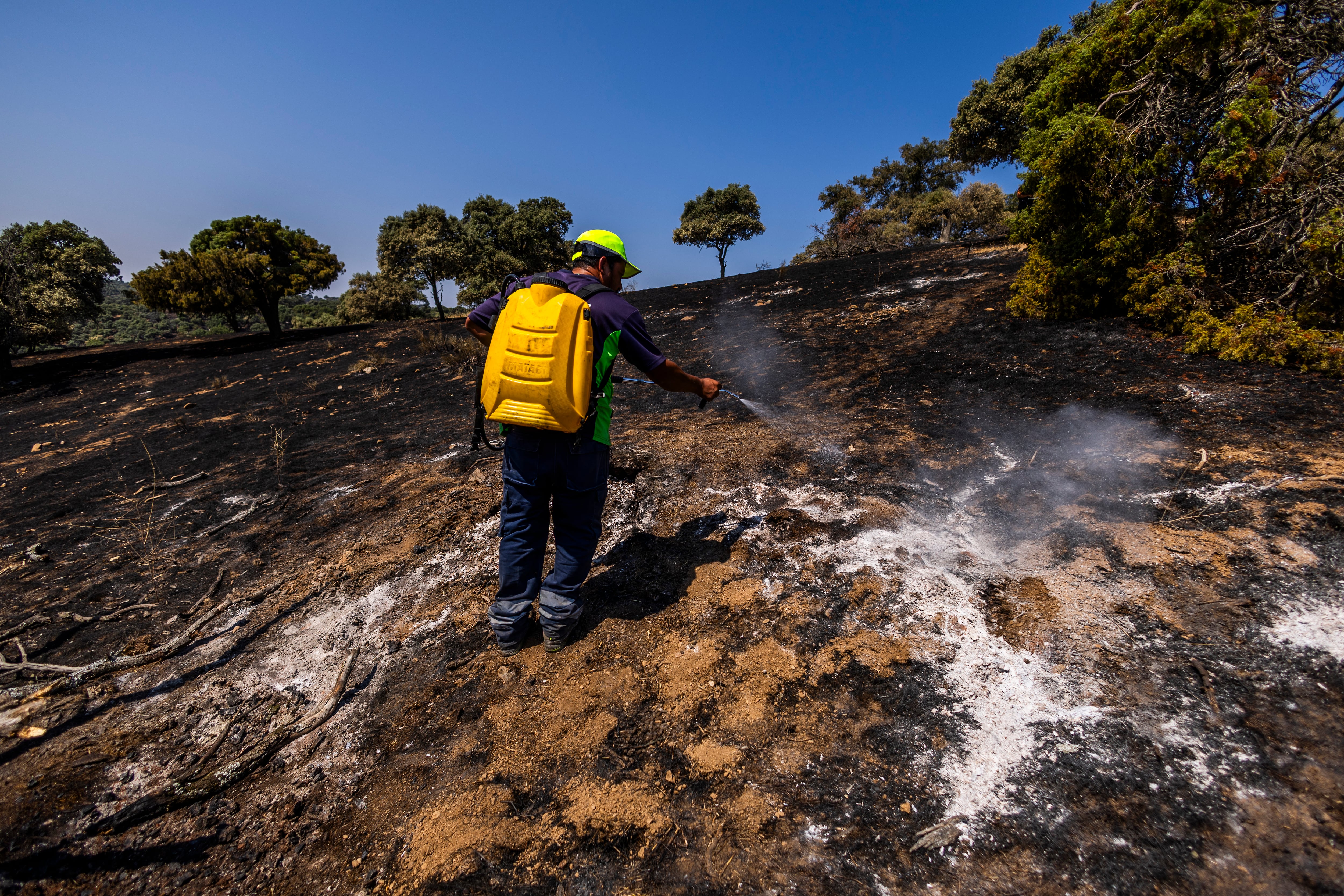 José Luis, Guardia Rural, y dos brigadistas, Carlos y Santi, apagan un conato de incendio en una finca cerca del pueblo Aldea del Fresno, en Madrid. SAMUEL SÁNCHEZ