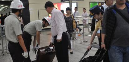 Seguranças revistam as bagagens dos passageiros na estação de trens de Guangzhou.
