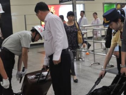 Seguranças revistam as bagagens dos passageiros na estação de trens de Guangzhou.