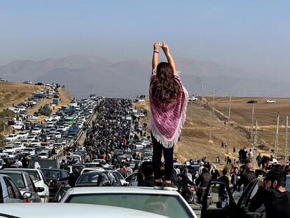 Una joven sobre el techo de un coche frente a la multitud que se dirigía el día 26 al cementerio donde está enterrada Mahsa Amini, en Saqqez (Irán).