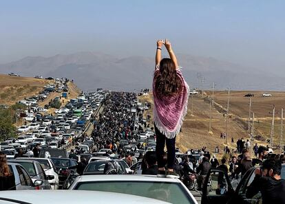 Una joven sobre el techo de un coche frente a la multitud que se dirigía el día 26 al cementerio donde está enterrada Mahsa Amini, en Saqqez (Irán).