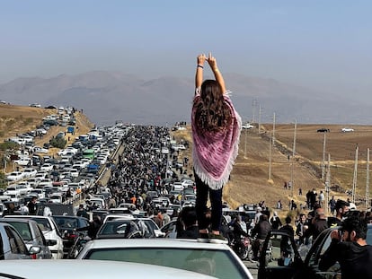 Una joven sobre el techo de un coche frente a la multitud que se dirigía el día 26 al cementerio donde está enterrada Mahsa Amini, en Saqqez (Irán).