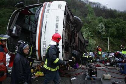 Varios miembros de los equipos de rescate trabajan en torno al autobús siniestrado ayer en Villallana (Asturias).