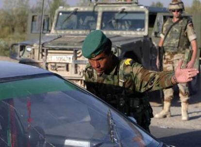 Un soldado afgano inspecciona un coche en un control en Herat acompañado por un soldado español, al fondo.