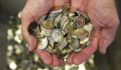 Un hombre sostiene varias monedas de euro.