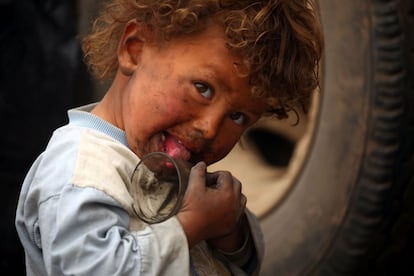 A displaced Syrian child, who fled the countryside surrounding the Islamic State (IS) group stronghold of Raqa, plays with a glass cup at a temporary camp in the village of Ain Issa on April 28, 2017. / AFP PHOTO / DELIL SOULEIMAN