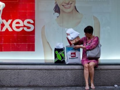 Una mujer ordena sus compras ante el escaparate de unos grandes almacenes