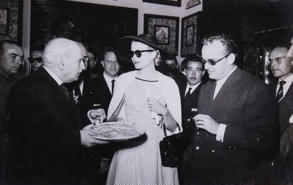 Grace Kelly y Rainiero Grimaldi observan un plato de cerámica que les muestra González Martí.