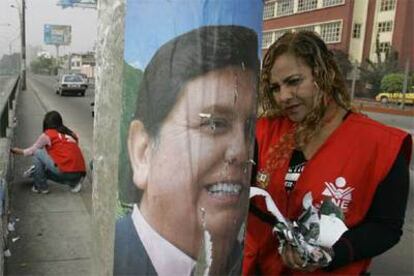 Una trabajadora retira un cartel electoral de Alan García en Lima.
