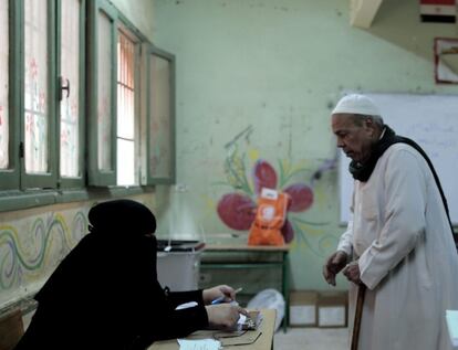 Un hombre espera a que se comprueben sus datos para proceder a realizar su votaci&oacute;n sobre el refer&eacute;ndum constitucional, en el barrio de Imbaba, El Cairo (Egipto).