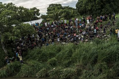 Decenas de migrantes esperan en la orilla guatemalteca su turno para cruzar el Suchiate.