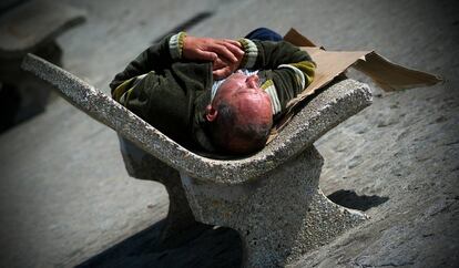 Una persona sin hogar duerme a la intemperie sobre un banco de A Coru&ntilde;a.