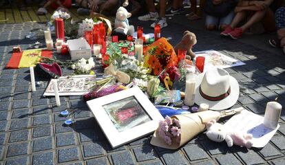 Personas sentadas al lado de un tributo a las víctimas del atentado de Barcelona, este viernes.