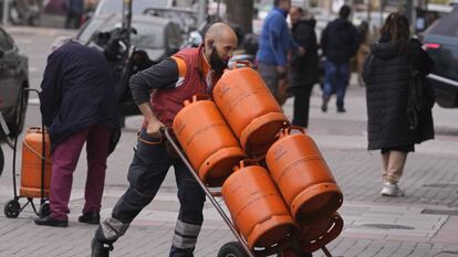 Un trabajador español transporta bombonas de gas.