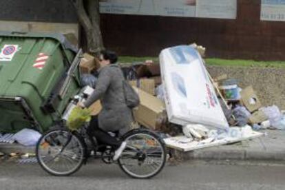 Una mujer camina en bicicleta por una de las calles de la localidad gaditana de Jerez de la Frontera, donde se acumulan más de tres mil toneladas de basuras debido a la huelga de los trabajadores del servicio de limpieza.