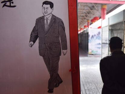 Un hombre camina junto a una imagen del presidente chino, Xi Jinping, este lunes en un mercado de Pequ&iacute;n.
 