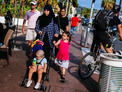 Muçulmana usando véu passeia com seus filhos na cidade francesa de Nice.