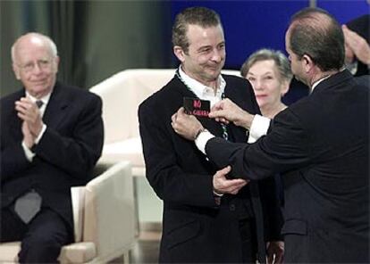 Chaves coloca la pegatina de "No a la guerra" al actor Juan Diego tras imponerle la Medalla de Andalucía.