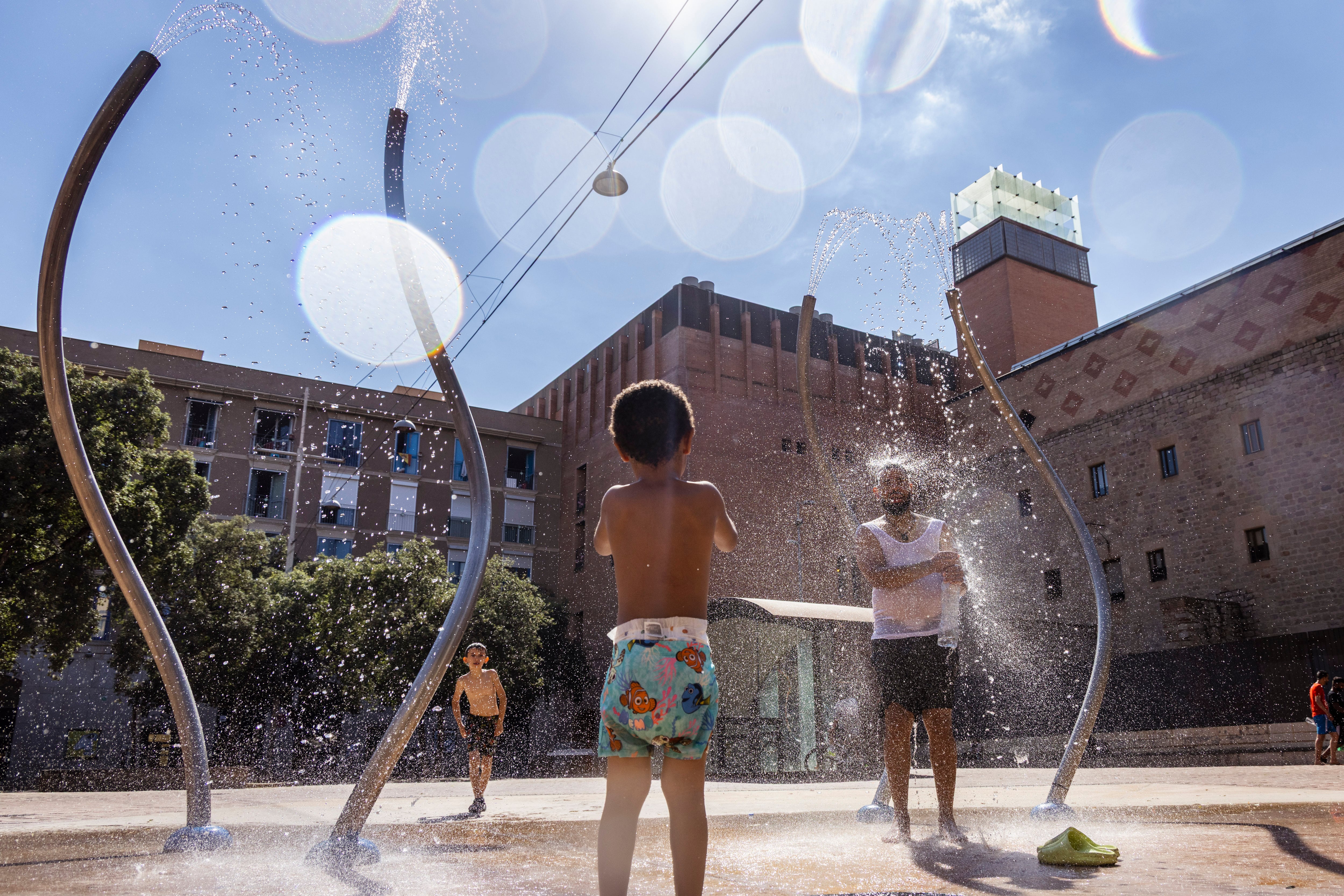 Niños durante la ola de calor en la Plaça de les Caramelles en el Raval.