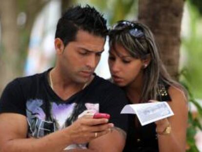 Dos jóvenes usan un teléfono móvil, en La Habana (Cuba). EFE/Archivo
