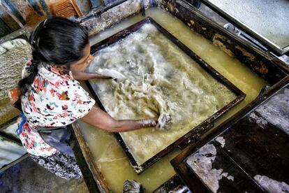 Una de las trabajadoras esparce la pasta de papel en la superficie de la pantalla enmarcada. Las boñigas de las que se nutre la fábrica de Kegalle provienen de la Millennium Elephant Foundation, una organización no gubernamental que se dedica a mejorar el bienestar de los paquidermos domésticos.