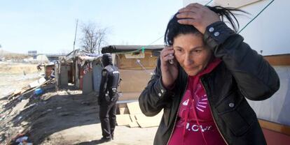 A woman speaks on the phone as a nearby police officer observes the demolition of shacks in El Gallinero.