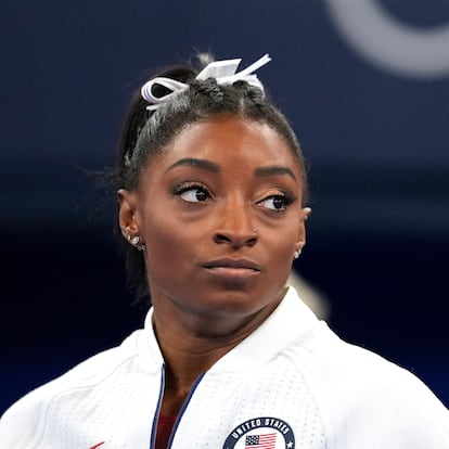 Simone Biles, of the United States, watches gymnasts perform after she exited the team final with apparent injury, at the 2020 Summer Olympics, Tuesday, July 27, 2021, in Tokyo. The 24-year-old reigning Olympic gymnastics champion Biles huddled with a trainer after landing her vault. She then exited the competition floor with the team doctor. (AP Photo/Ashley Landis)