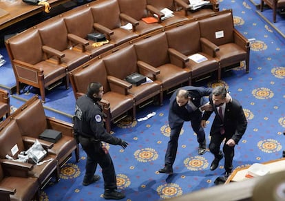 Los miembros del congreso corren a cubrirse mientras los manifestantes intentan ingresar a la Cámara de la Cámara durante una sesión conjunta del Congreso