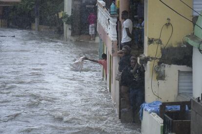Varias personas observan una calle inundada en Santiago de los Caballeros (República Dominicana). 