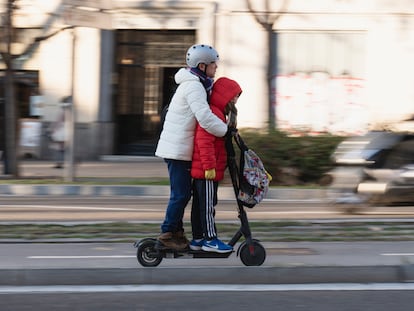 Un adulto se transporta junto a un menor en un patinete en la plaza Tetuán de Barcelona.